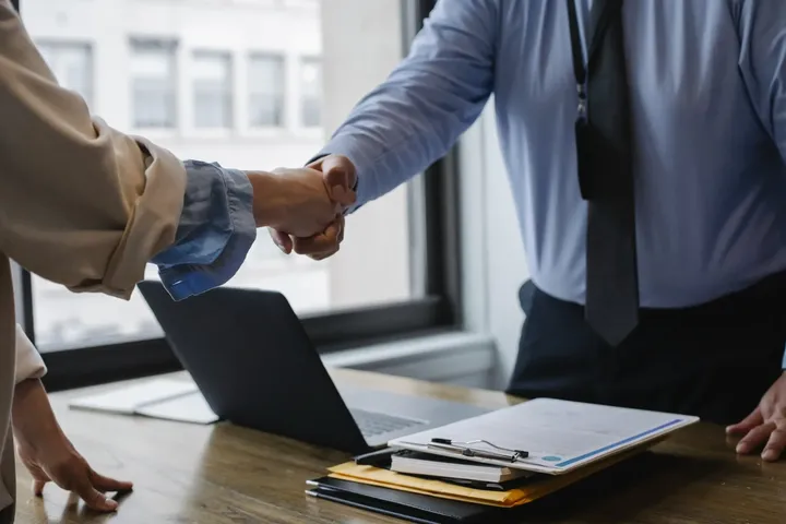 Two people shaking hands in agreement over a desk.  Madisonville, Louisiana